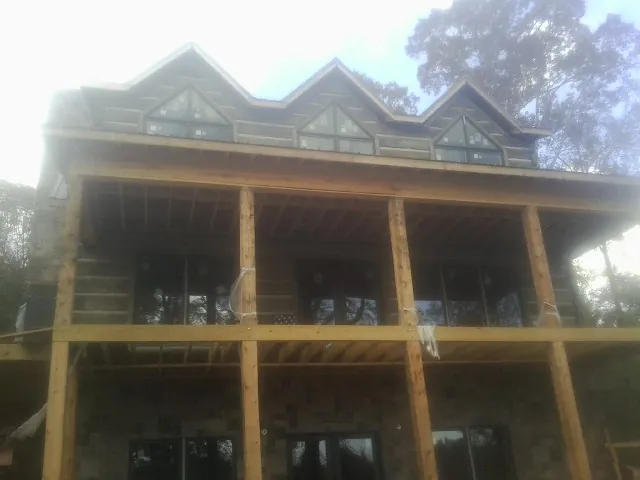 Dormers and porch framing on a large log home under construction — Roof Coating work by our crew in Wood Lake