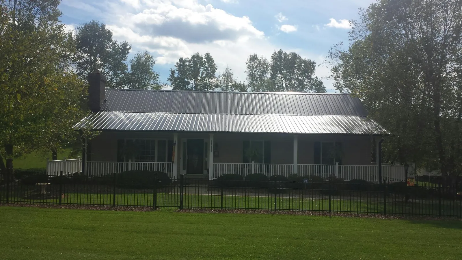 Gray metal roof on a brick ranch with a full width front porch — Gutter Guard Installation work by our crew in Wood Lake