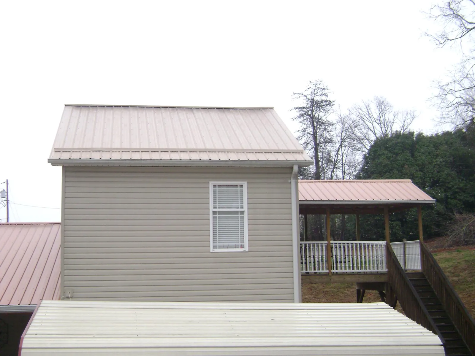 Tan metal roofs on a two story addition and attached porch, from a Roof Replacement job in Wood Lake