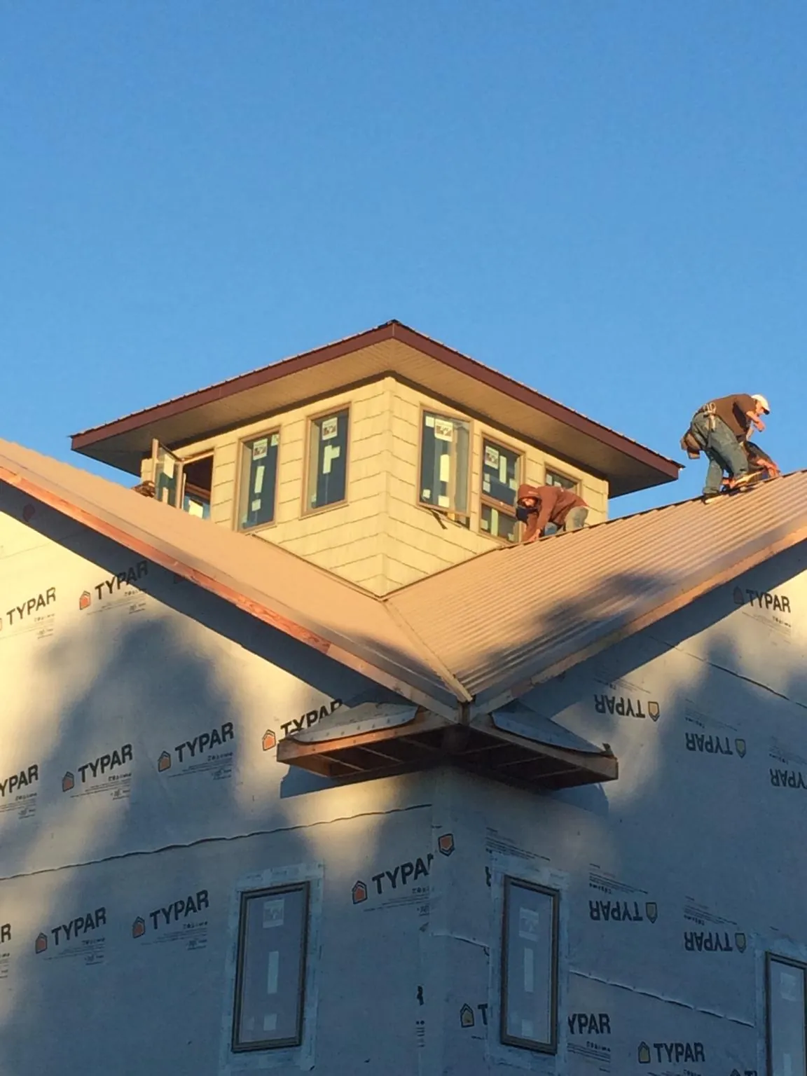 Roofers working around a rooftop cupola on a new metal roof at sunset — Roof Waterproofing in Wood Lake by Roofing Brothers